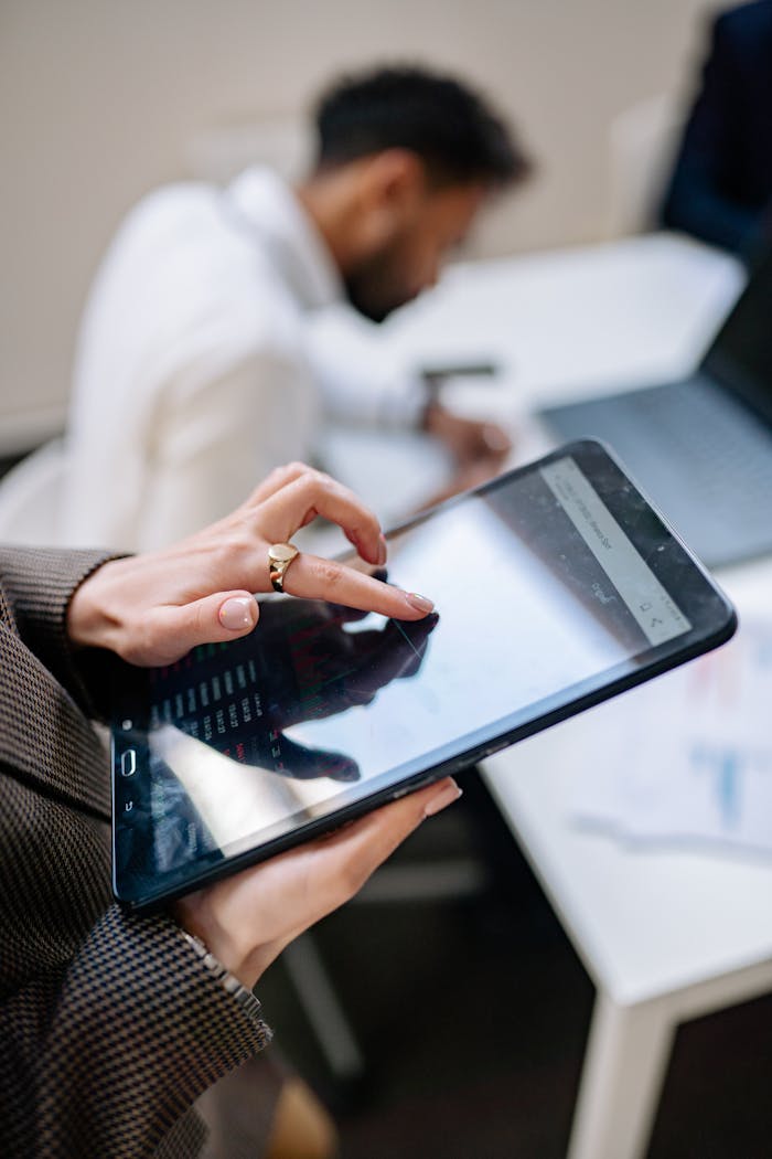 why-choose-us-02 Close-up of a person using a tablet in an office setting, focusing on technology at work.